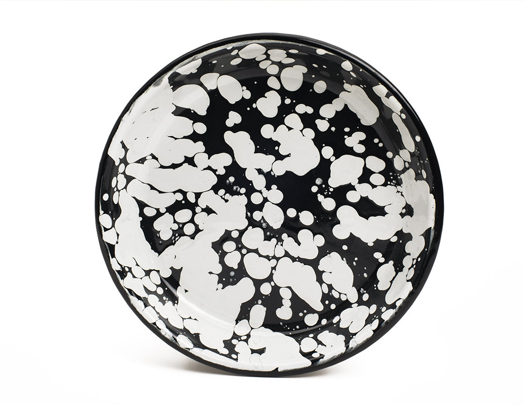 Plato hondo de peltre negro con manchas blancas y borde negro